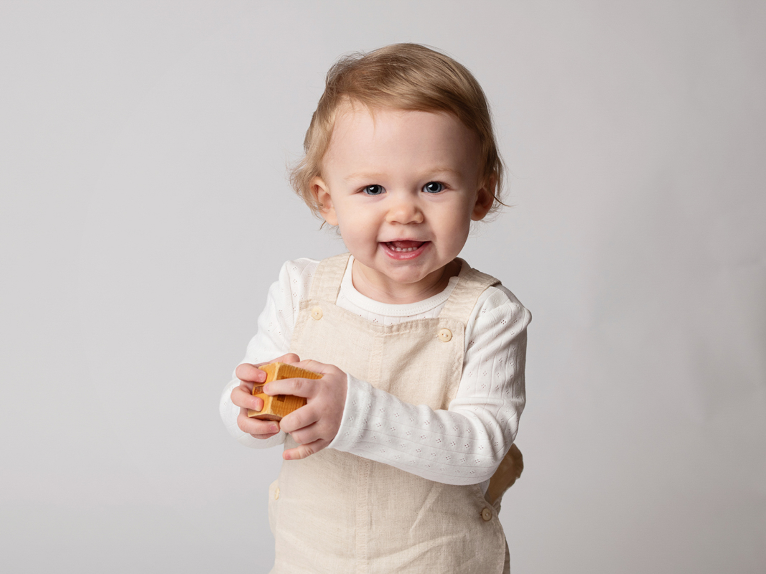 Barnfotografering i studio med busig 1 åring som håller i en kloss