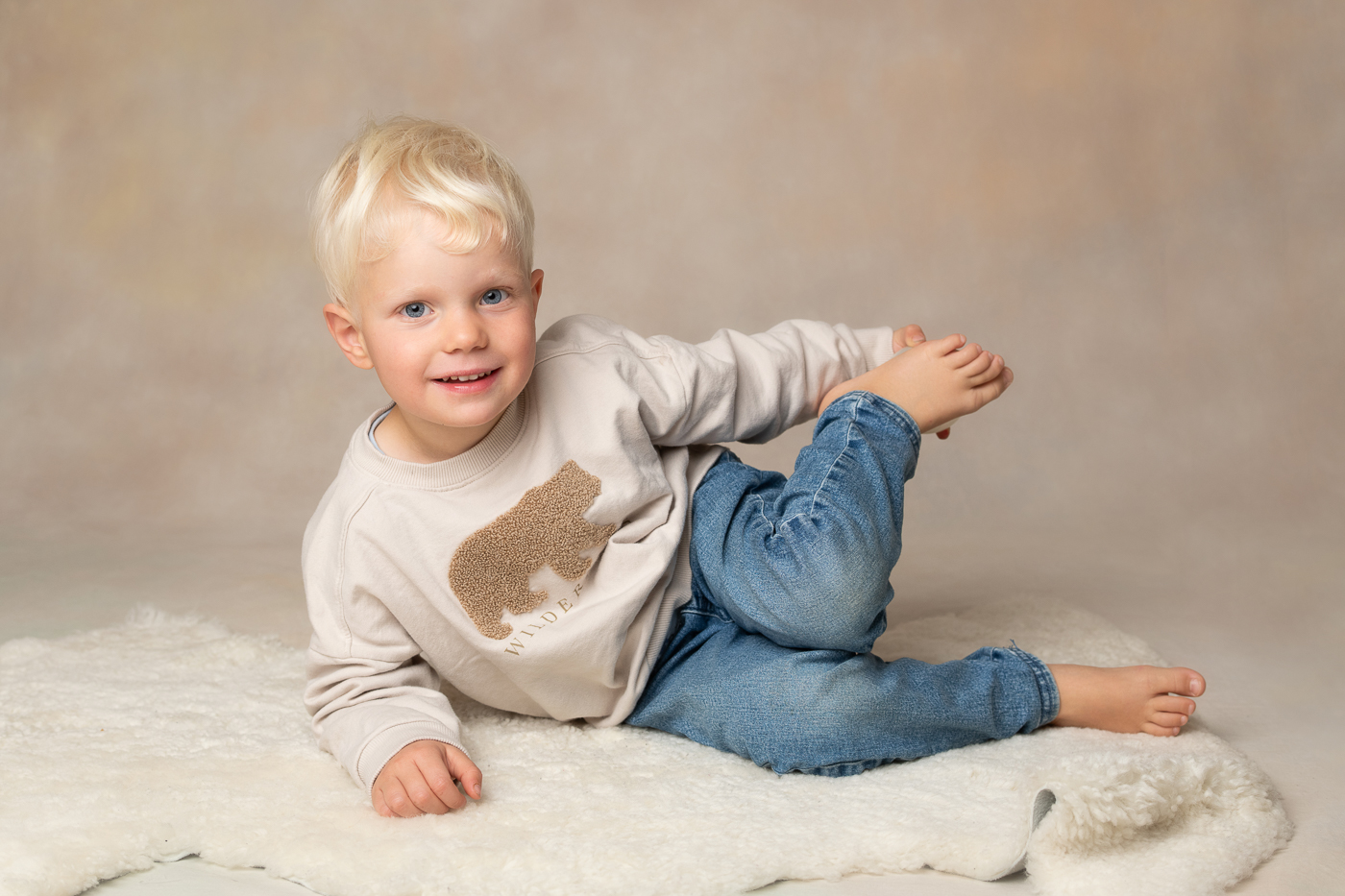 Barnfotografering i studio med pojke som ligger på golvet